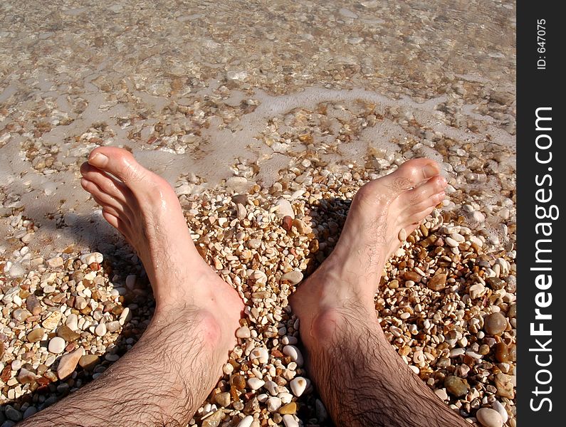 Looking at feet in water sand and stones of Southern Italy. Looking at feet in water sand and stones of Southern Italy