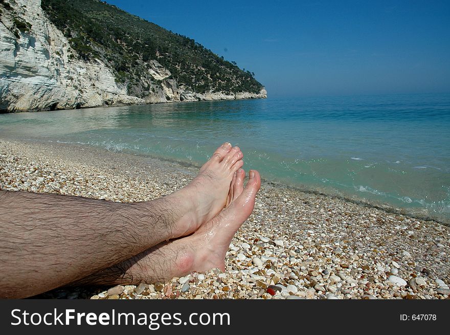 Looking at feet in water sand and stones of Southern Italy. Looking at feet in water sand and stones of Southern Italy