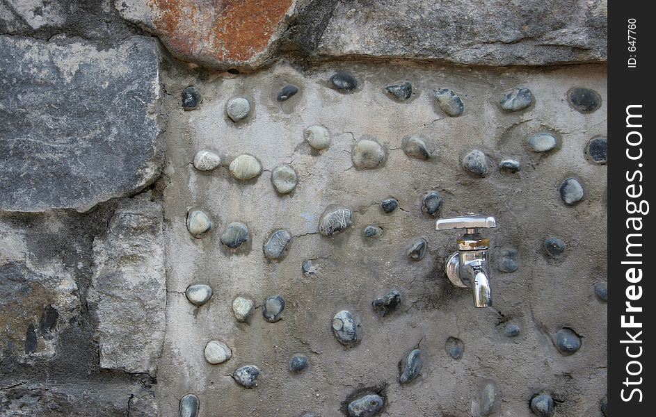 Silver tap on concrete and stone wall