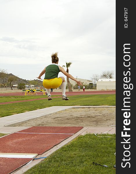 A competitor in the women's long jump event during a college track meet.