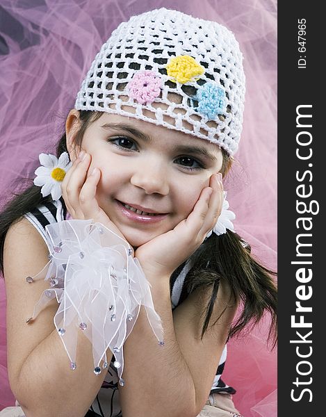 Sweet little girl poses like a spoiled kid in all sorts of new clothes on a pink, veil background