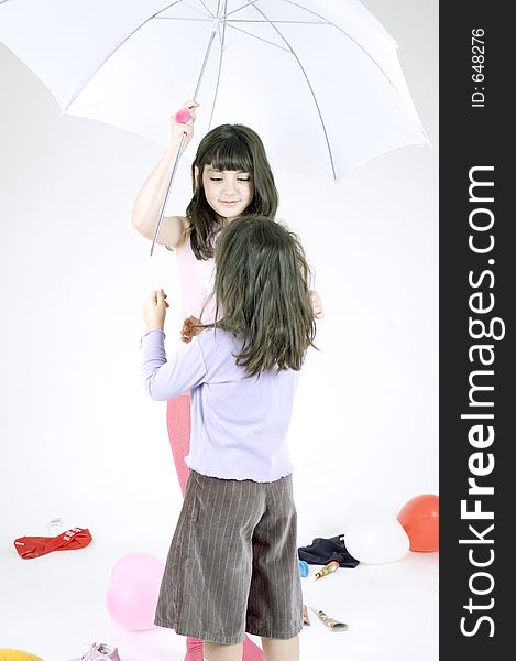 Two little sisters playing with an umbrella, the older girl not wanting to share it with her younger sister. Two little sisters playing with an umbrella, the older girl not wanting to share it with her younger sister.