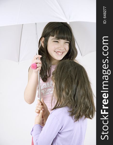 Two little sisters happily sharing an umbrella. Two little sisters happily sharing an umbrella.