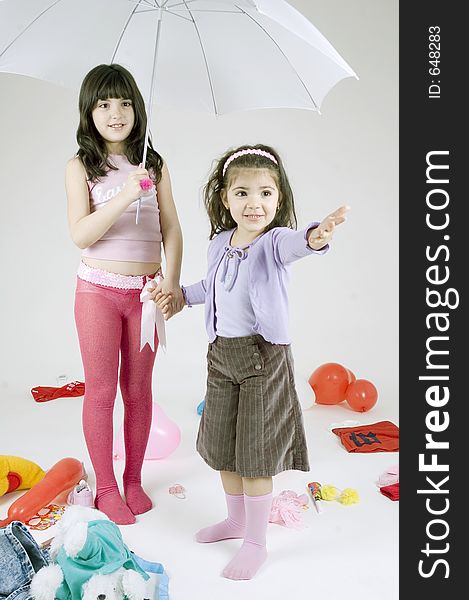 Two cute young sisters playing with an umbrella. Two cute young sisters playing with an umbrella.