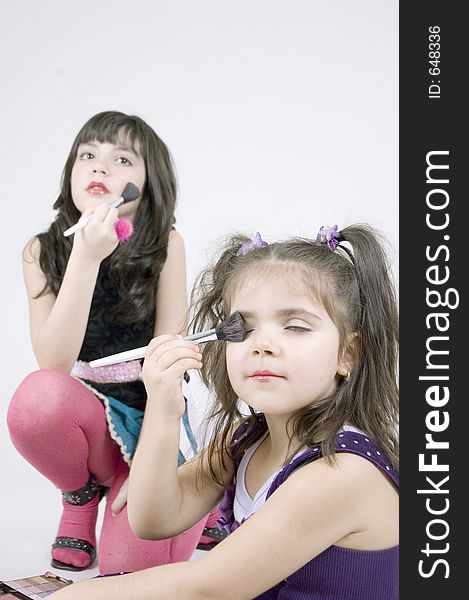 Two little sisters, a seven and a three year old playing with make-up, having fun