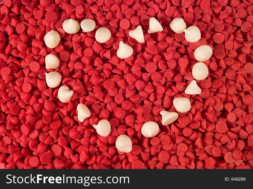 White chocolate chips arranged into a heart shape on a bed of cherry baking chips. White chocolate chips arranged into a heart shape on a bed of cherry baking chips.