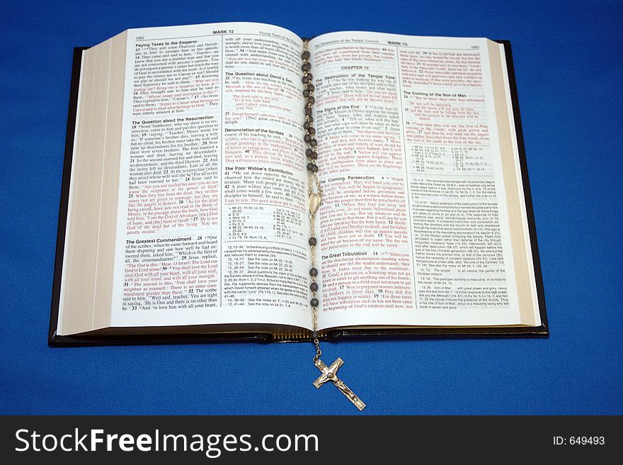 Holy Bible and rosary on blue background