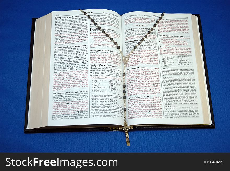 Holy Bible and rosary on blue background