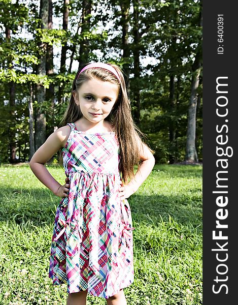 Beautiful little girl modeling a plaidd dress in an outdoor setting with long brown hair. Beautiful little girl modeling a plaidd dress in an outdoor setting with long brown hair.