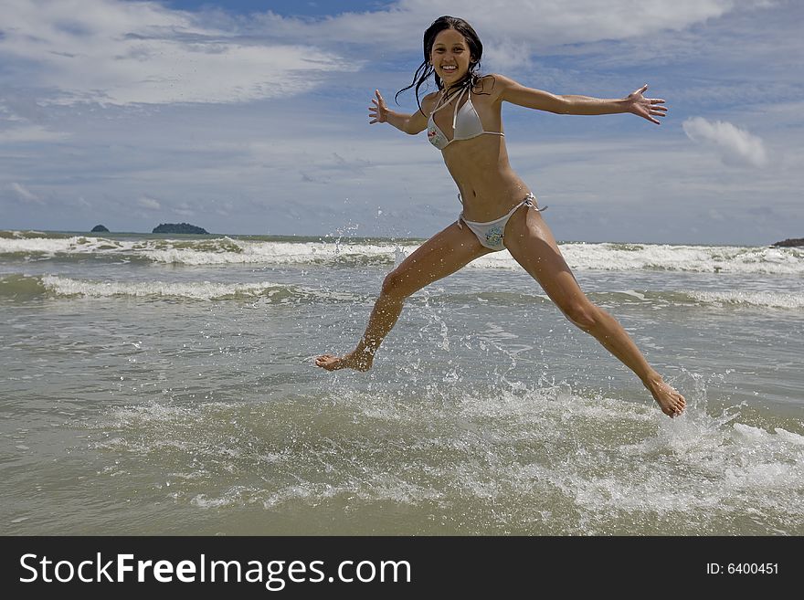 Female teenager jumps on the beach and signals joy in the vacation