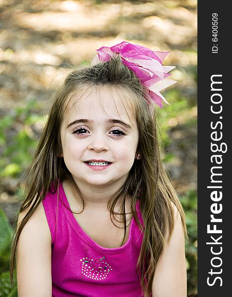 Beautiful little girl with a big pink bow in her hair. She has a beautiful smile with perfect baby teeth. Beautiful little girl with a big pink bow in her hair. She has a beautiful smile with perfect baby teeth.