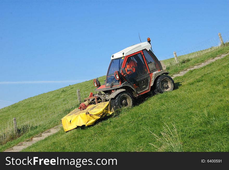 Tractor lawnmower mowing the grass riding down a. Tractor lawnmower mowing the grass riding down a