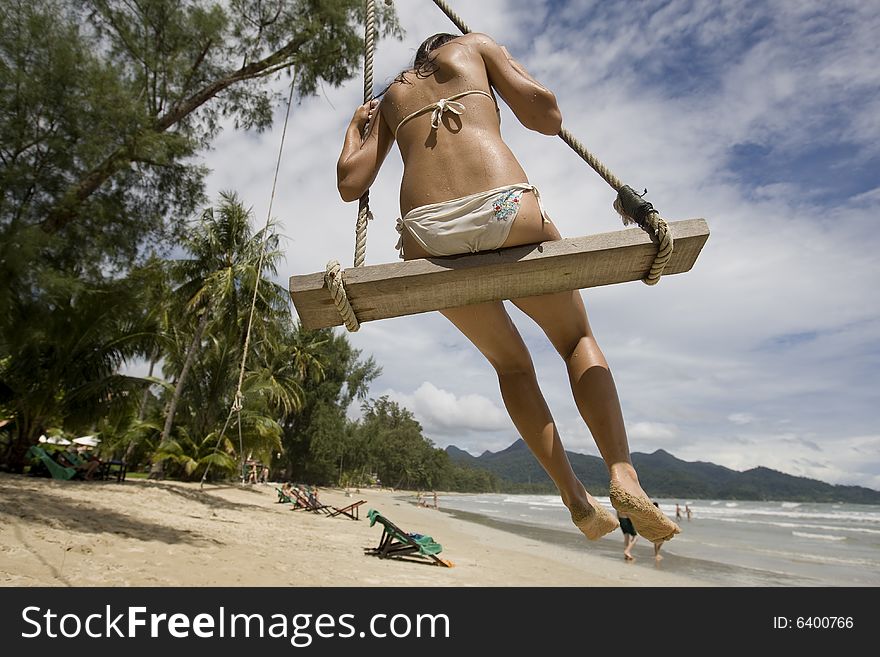 Girl on swing on the beach enjoys the vacation