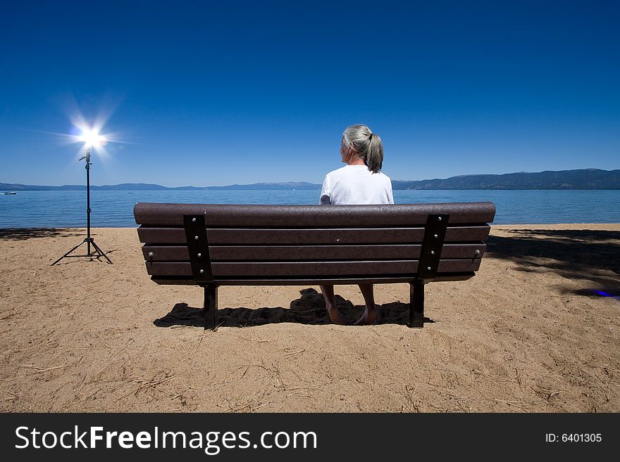 Senior woman sitting on bench looking out on blue water. Senior woman sitting on bench looking out on blue water