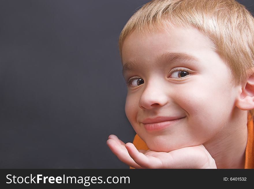 Friendly boy with an orange shirt against a black background