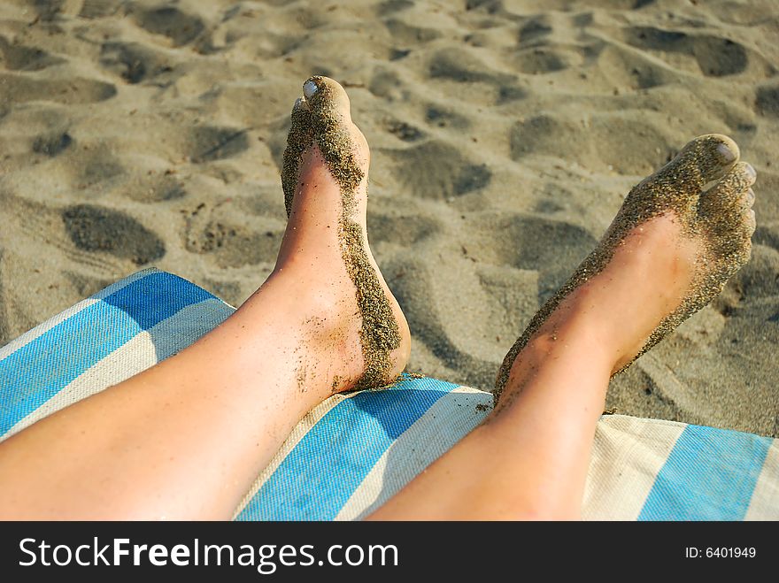 Pair of a woman's feet over the chair on the beach