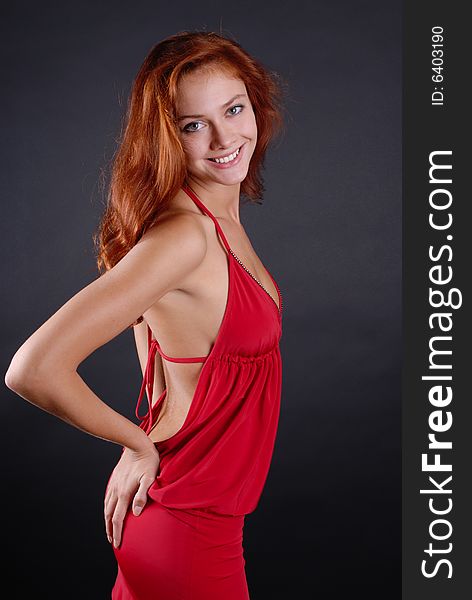 Beautiful redheaded girl posing in studio on dark background