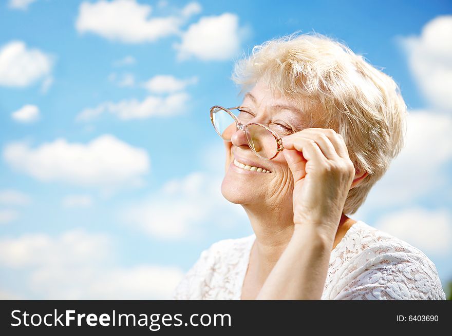 Portrait of the laughing elderly woman with glasses against the sky. Portrait of the laughing elderly woman with glasses against the sky