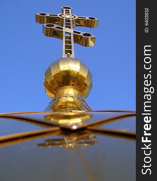 A gold cross is highly in dark blue sky. A gold cross is highly in dark blue sky