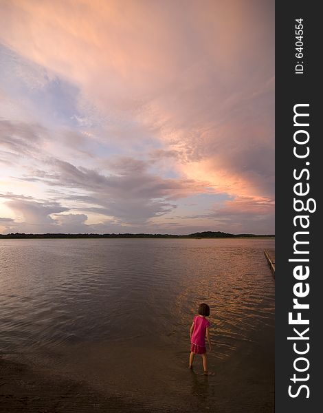 Little girl looking over water at sunset