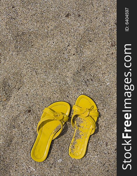 Yellow flip-flops on sand