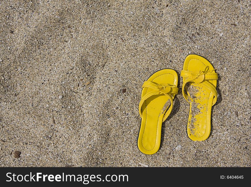 Yellow flip-flops on sand