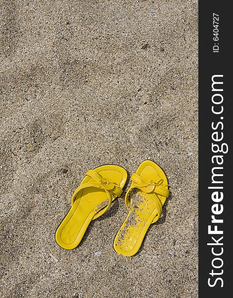 Yellow flip-flops on sand