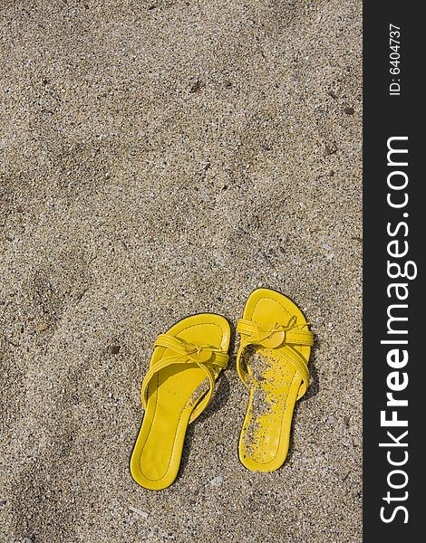 Yellow flip-flops on sand