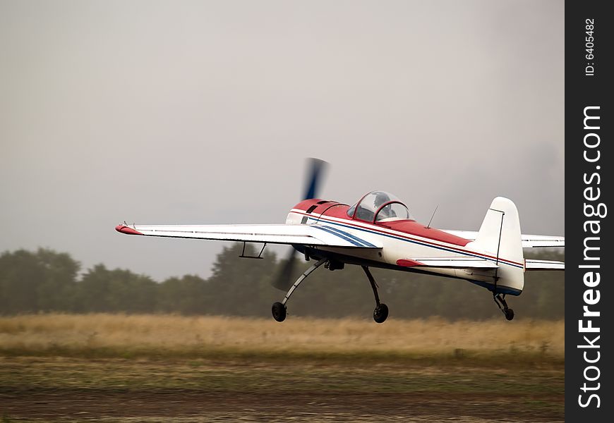 Small aerobatics plane landing on dirt runway. Small aerobatics plane landing on dirt runway