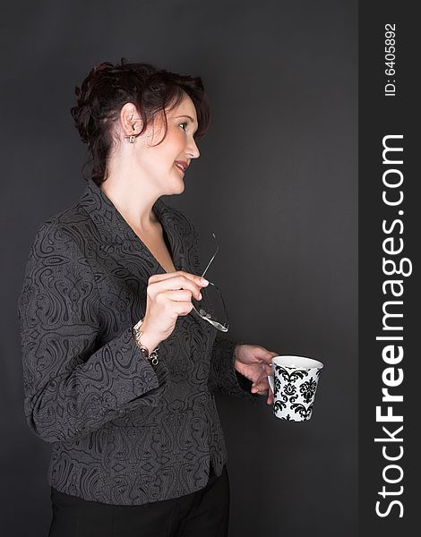 Composed Businesswoman holding a mug against a black background. Composed Businesswoman holding a mug against a black background