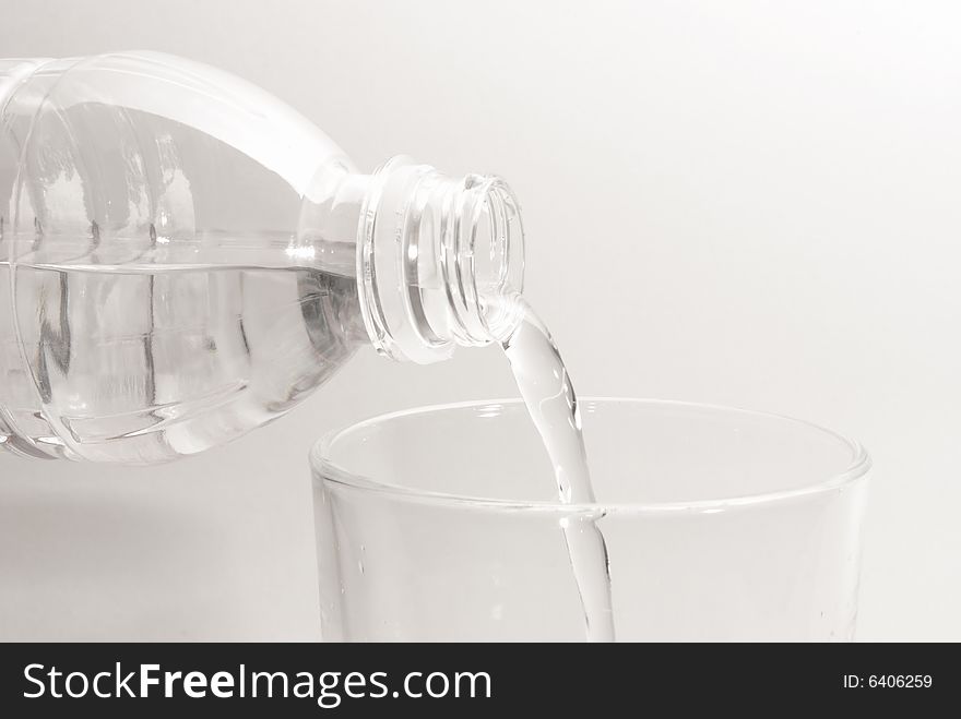 Some bottled water is being poured into a glass. Some bottled water is being poured into a glass.
