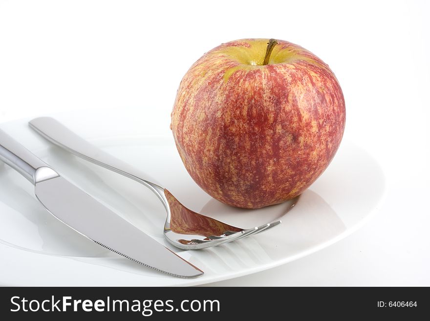 Cutlery and an apple on a plate