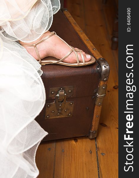 Young bride sitting with her foot on a suitcase