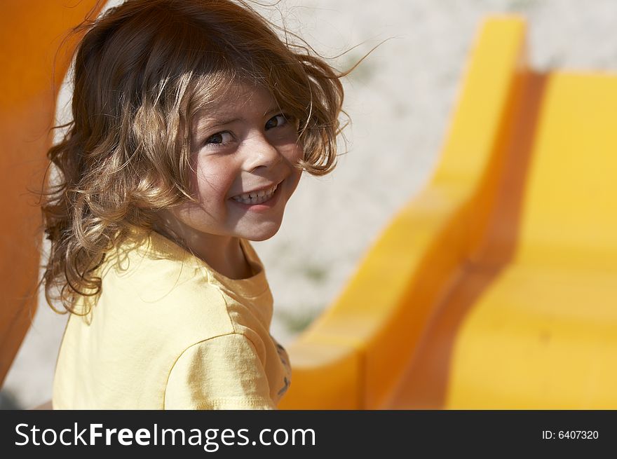 A picture of a cute little girl smiling on slide. A picture of a cute little girl smiling on slide