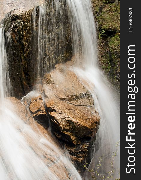 Small waterfall over red rock. Close up.