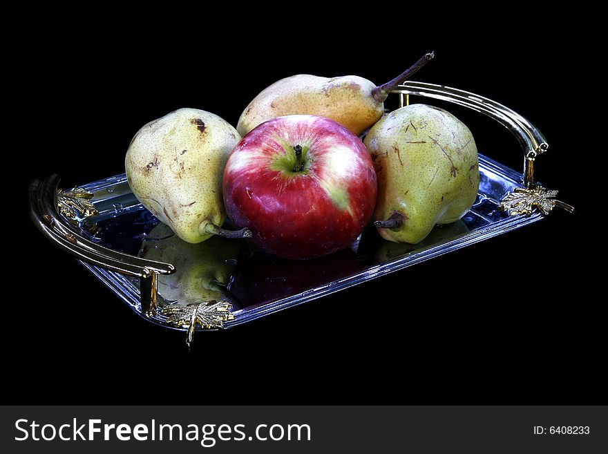 Pears and apple on tray on black background