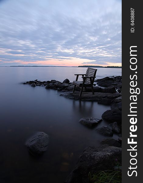 Sunset by the lake with empty chair, long exposure