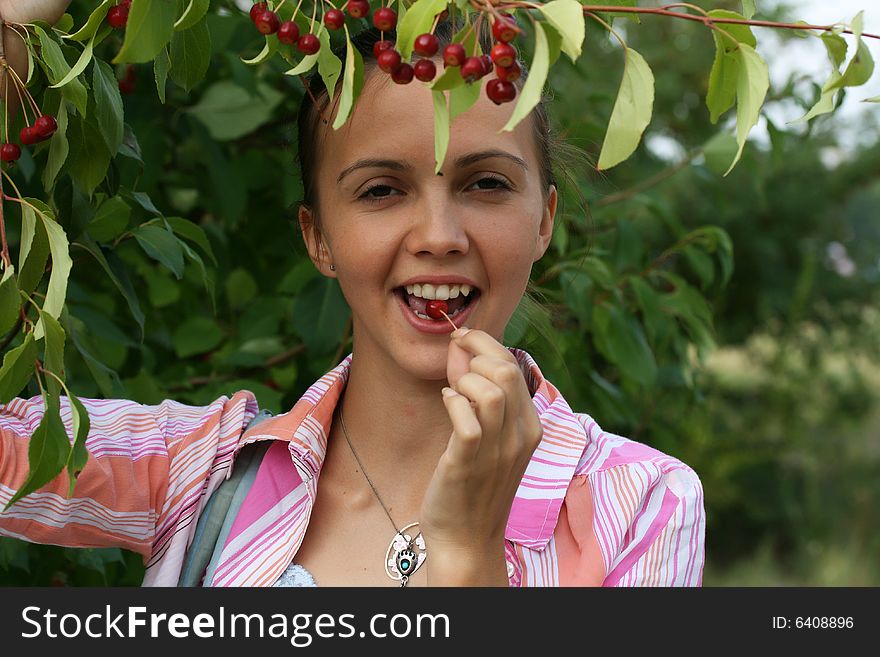 Portrait of girl with a berry on a background greenery