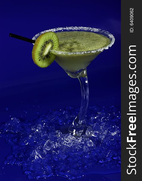 Green cocktail with foam, kiwi on blue background. Green cocktail with foam, kiwi on blue background