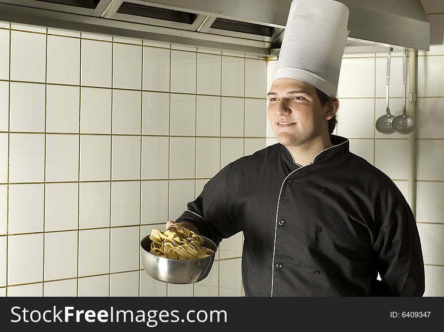 Smiling chef standing holding a bowl of noodles. Horizontally framed photo. Smiling chef standing holding a bowl of noodles. Horizontally framed photo.