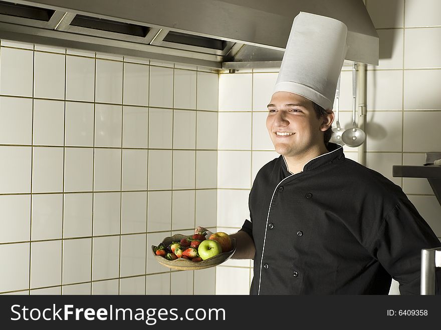 Chef's arm holding out a fruit plate with apples, strawberries, eggs, and blackberries on it. Horizontally framed photo. Chef's arm holding out a fruit plate with apples, strawberries, eggs, and blackberries on it. Horizontally framed photo.