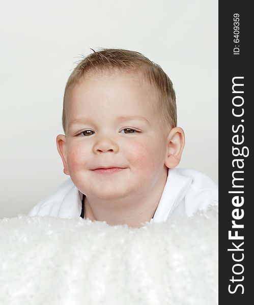A young baby is smiling at the camera in a studio.  Vertically framed shot. A young baby is smiling at the camera in a studio.  Vertically framed shot.
