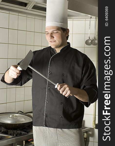 Chef sharpening a knife with a serious look on his face. Vertically framed photo. Chef sharpening a knife with a serious look on his face. Vertically framed photo.