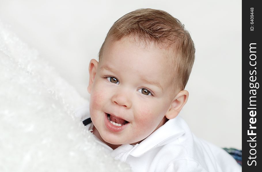 A young baby is smiling at the camera in a studio.  Horizontally framed shot. A young baby is smiling at the camera in a studio.  Horizontally framed shot.