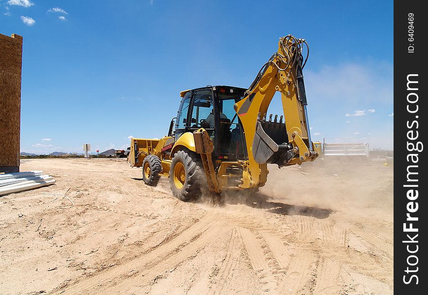 Photo of backhoe driving through dirt at a new construction site. Horizontally framed photo. Photo of backhoe driving through dirt at a new construction site. Horizontally framed photo.