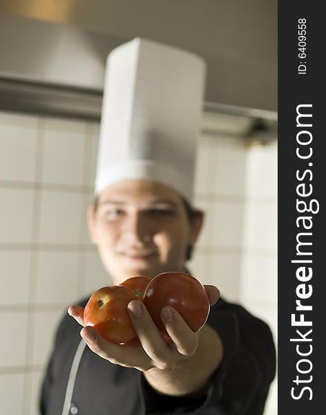 Smiling chef holding out three tomatoes. Vertically framed photo. Smiling chef holding out three tomatoes. Vertically framed photo.