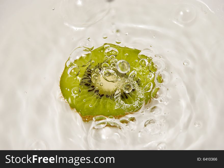 Slice of kiwi fruit and water on white background