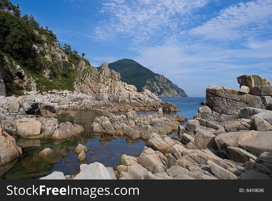 A landscape on Japanese sea. The rocks are on foreground. A cape and sky are on background. A landscape on Japanese sea. The rocks are on foreground. A cape and sky are on background.