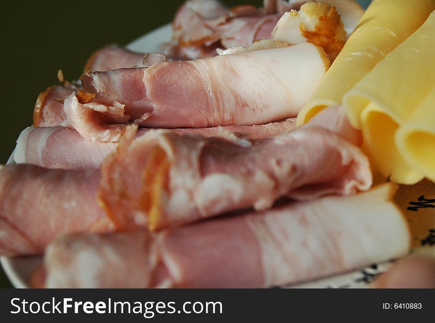 Slices of yellow cheese and ham on a plate. Slices of yellow cheese and ham on a plate