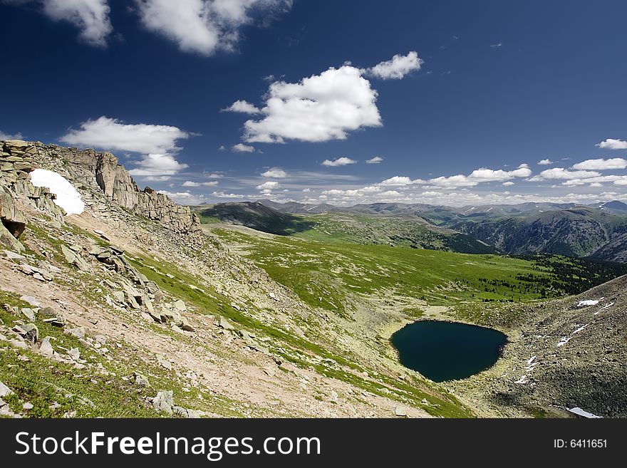 Lake in high mountains of Altai, summer, blue sky and white clouds